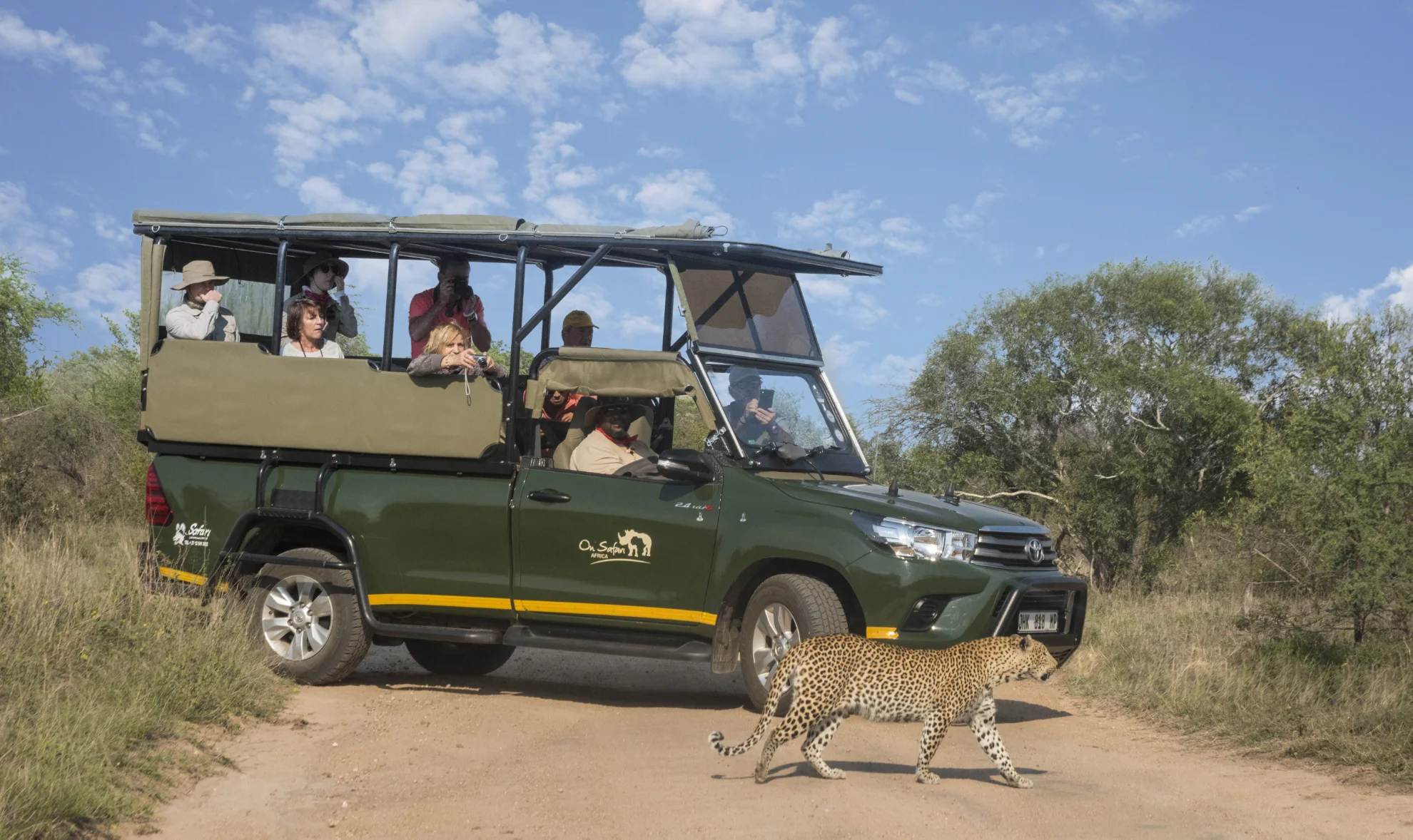 Guide and guests in an open safari vehicle on a Kruger National Park game drive